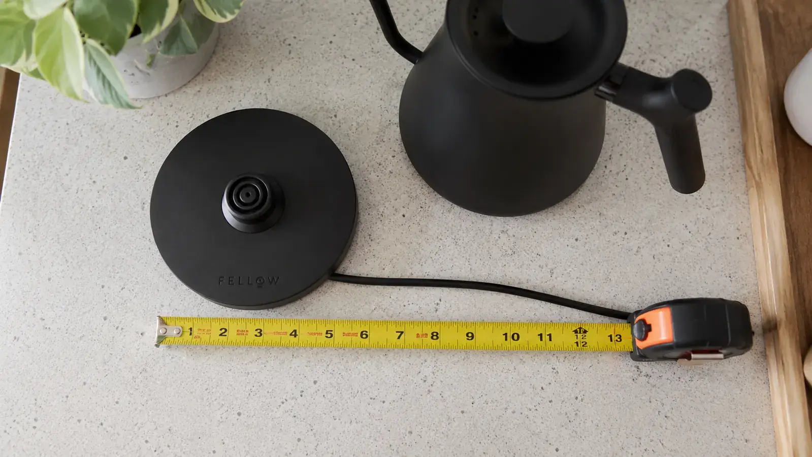 Cosori kettle base with measuring tape showing cord length on a kitchen counter