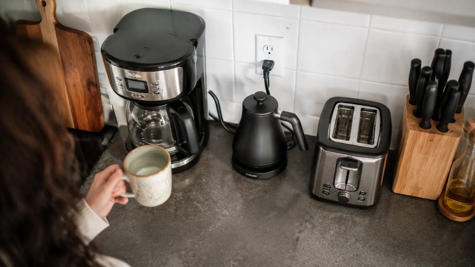 Small kitchen counter with the Cosori kettle tucked between a coffee maker and a toaster, showing its compact footprint