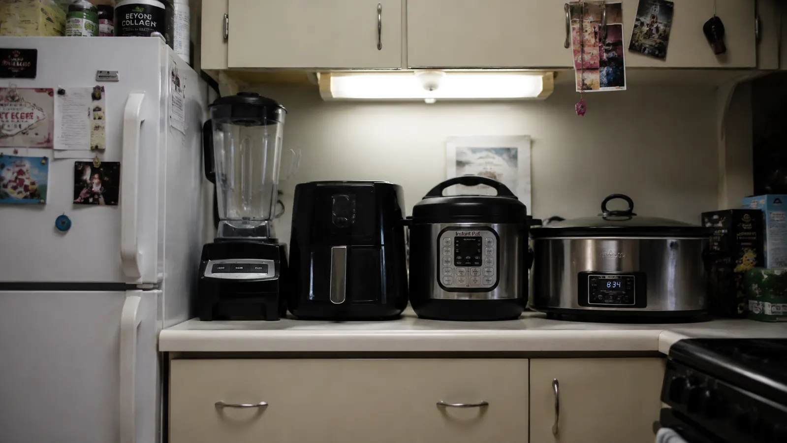 Four old kitchen appliances -- a slow cooker, rice cooker, steamer, and yogurt maker -- lined up on a counter showing how much space they consumed
