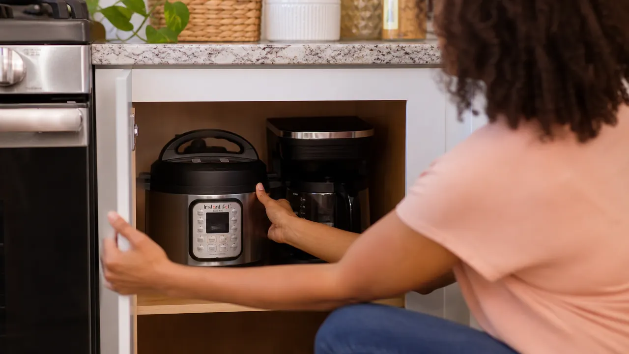 Instant Pot Mini stored in an open kitchen cabinet alongside other small appliances