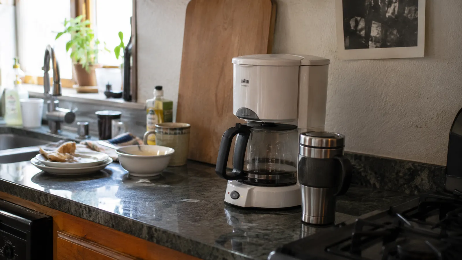 Mr. Coffee 5-Cup Mini coffee maker sitting on a cluttered apartment counter next to a travel mug, morning light, real-kitchen feel