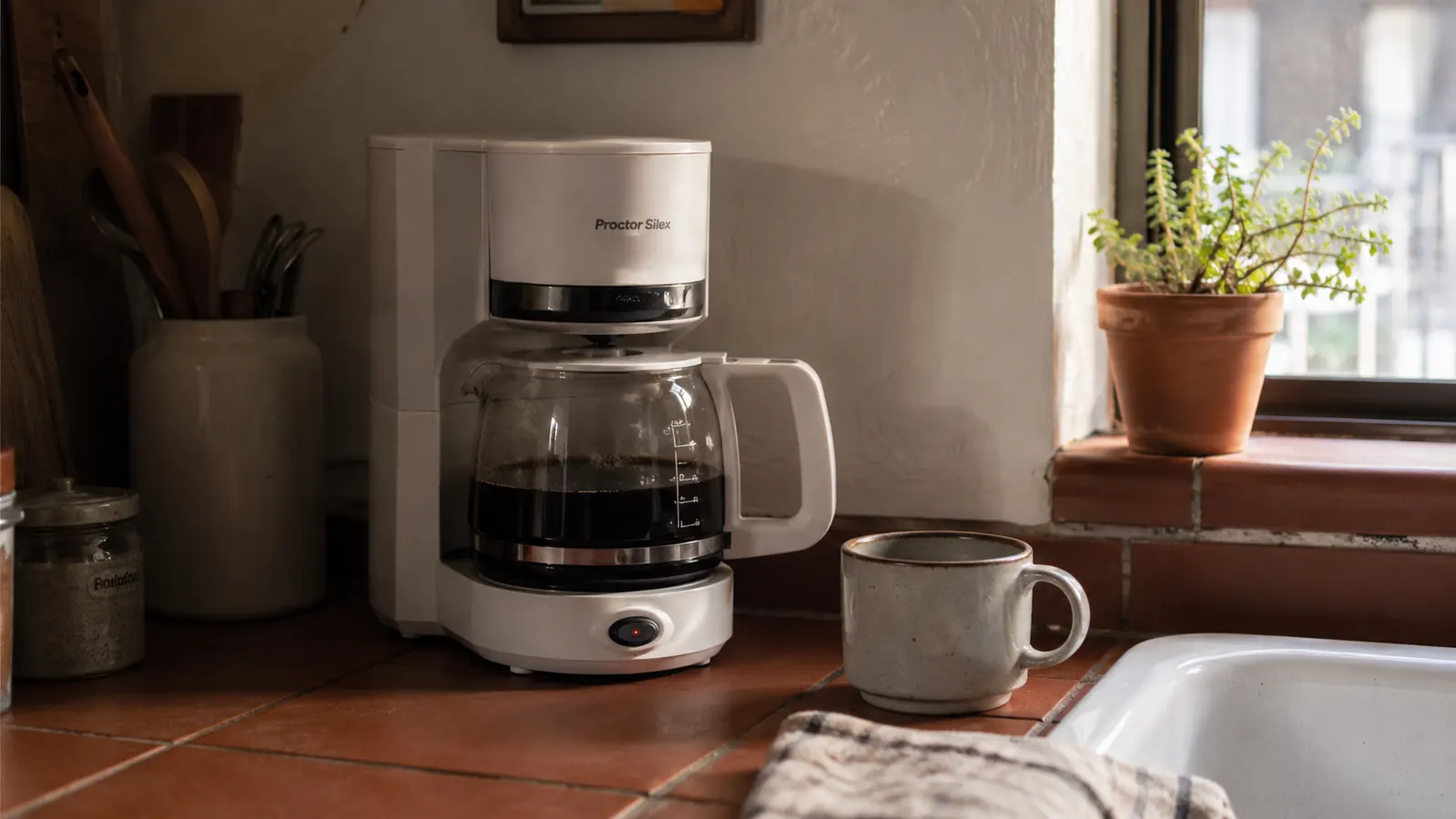 Mr. Coffee 5-Cup Mini brewer sitting on a small apartment kitchen counter next to a coffee mug