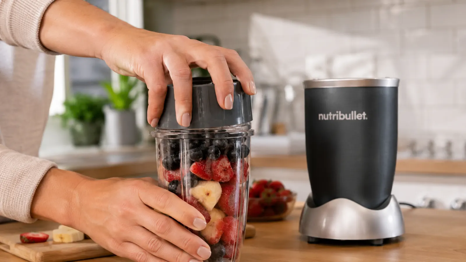 Person screwing the NutriBullet blade assembly onto the cup before blending, close-up of hands